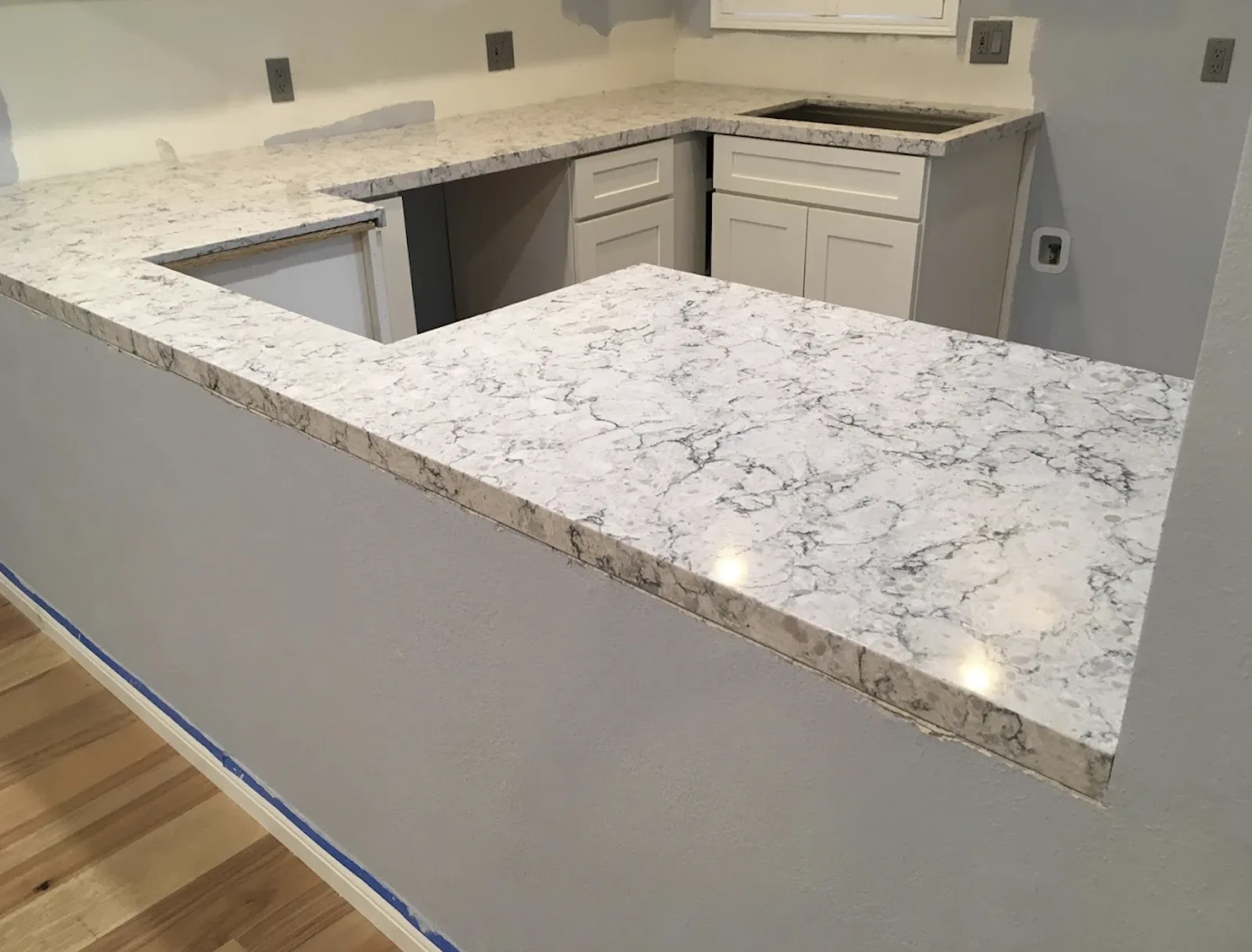 White veined quartz countertops installed on white shaker cabinets before backsplash and sink installation